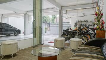 A modern interior with a glass partition, a sofa, a glass coffee table, and a motorcycle in the background.
