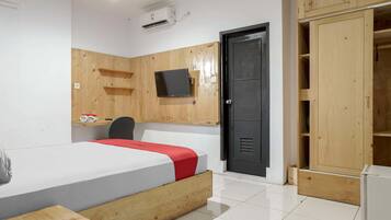 A bedroom with a bed, a TV, a wardrobe, and a desk.