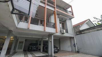 A multi-story residential building with a covered parking area.