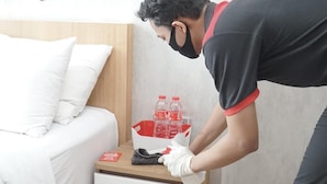 A hotel room with a bed, a wooden nightstand, and a red bottle of water. - RedDoorz near Terminal Condong Catur (Depok)