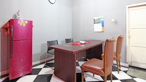 A room with a red refrigerator, a wooden table, and two chairs. - RedDoorz near Terminal Condong Catur (Depok)