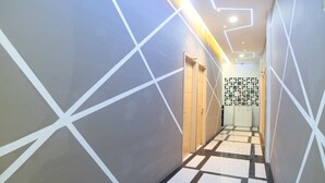 Un pasillo con diseños geométricos en las paredes, suelo a cuadros y un revestimiento mural con estampado al final.