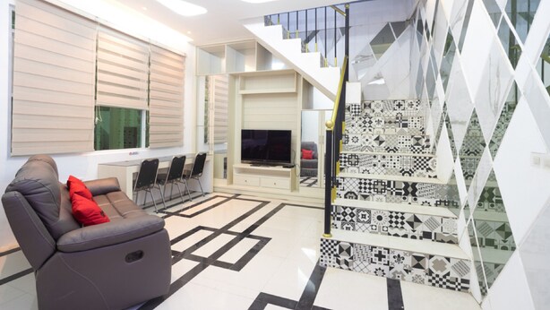 Una sala de estar moderna con un sofá, televisor y una escalera con baldosas estampadas.