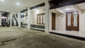 A building with a covered outdoor area, a staircase, and a door with curtains.