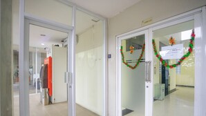 A lobby with a glass door leading to a hallway, a vending machine, and a sign indicating a lobby lift. - RedDoorz Apartment @ Bogor Valley (Bogor)