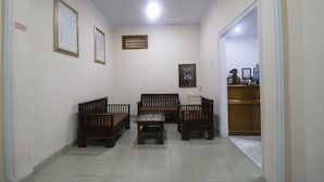 A hallway with a wooden bench, a small table, and a poster on the wall. - RedDoorz Plus near WTC Batanghari Mall (Jambi)