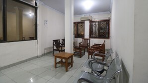 A waiting area with chairs, a table, and a large window. - RedDoorz Plus near WTC Batanghari Mall (Jambi)