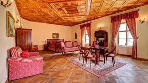 A cozy living room with a wooden ceiling, a sofa, chairs, a dining table, and a patterned rug. - Penzión Cosmopolitan II. (Banska Stiavnica)