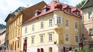 A yellow building with a red roof and multiple windows. - Penzión Cosmopolitan II. (Banska Stiavnica)