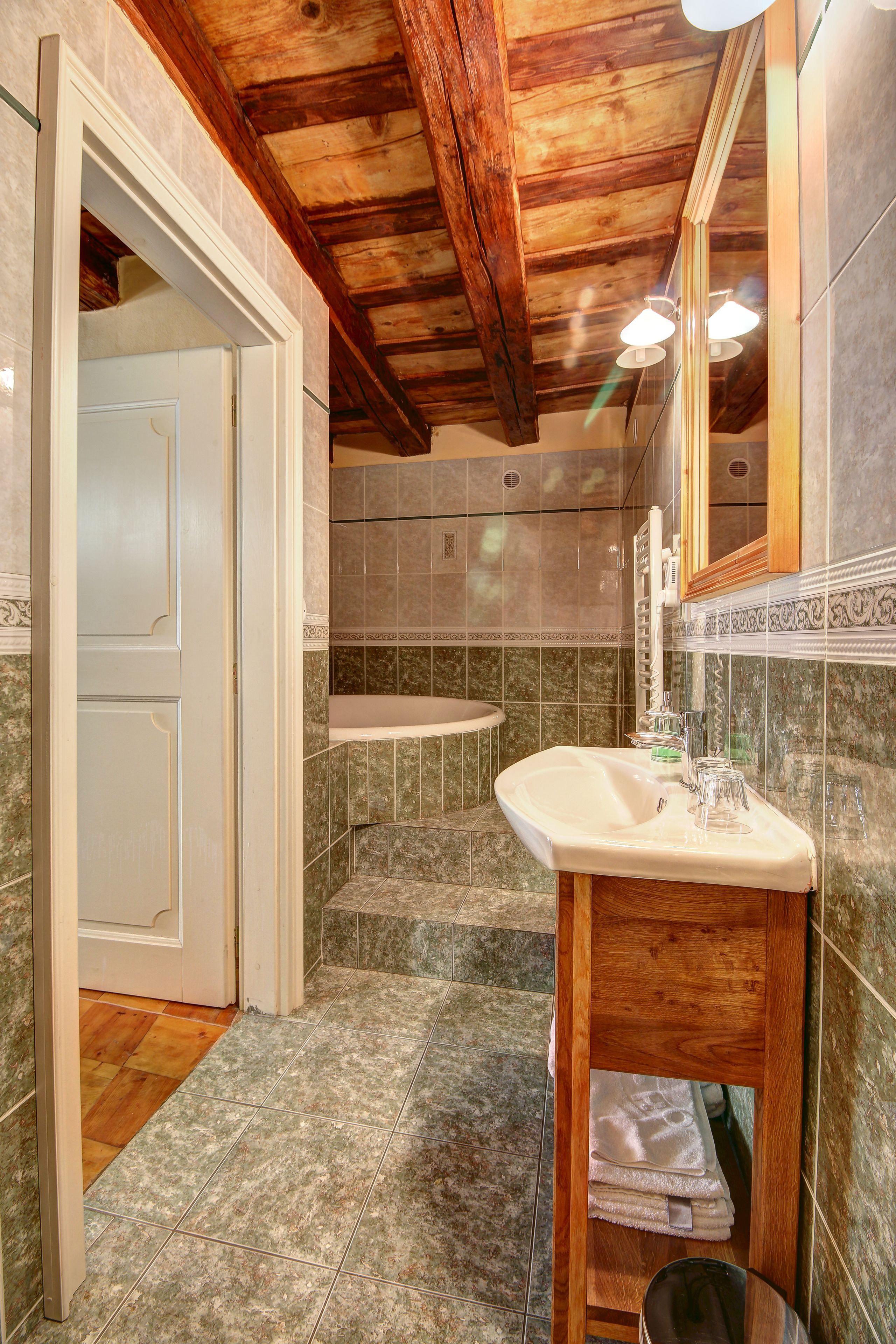 Un baño con techo de madera, un lavamanos y un espejo.