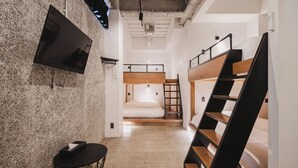 Ein modernes Interieur mit Etagenbetten, einem Fernseher und einem kleinen Tisch.