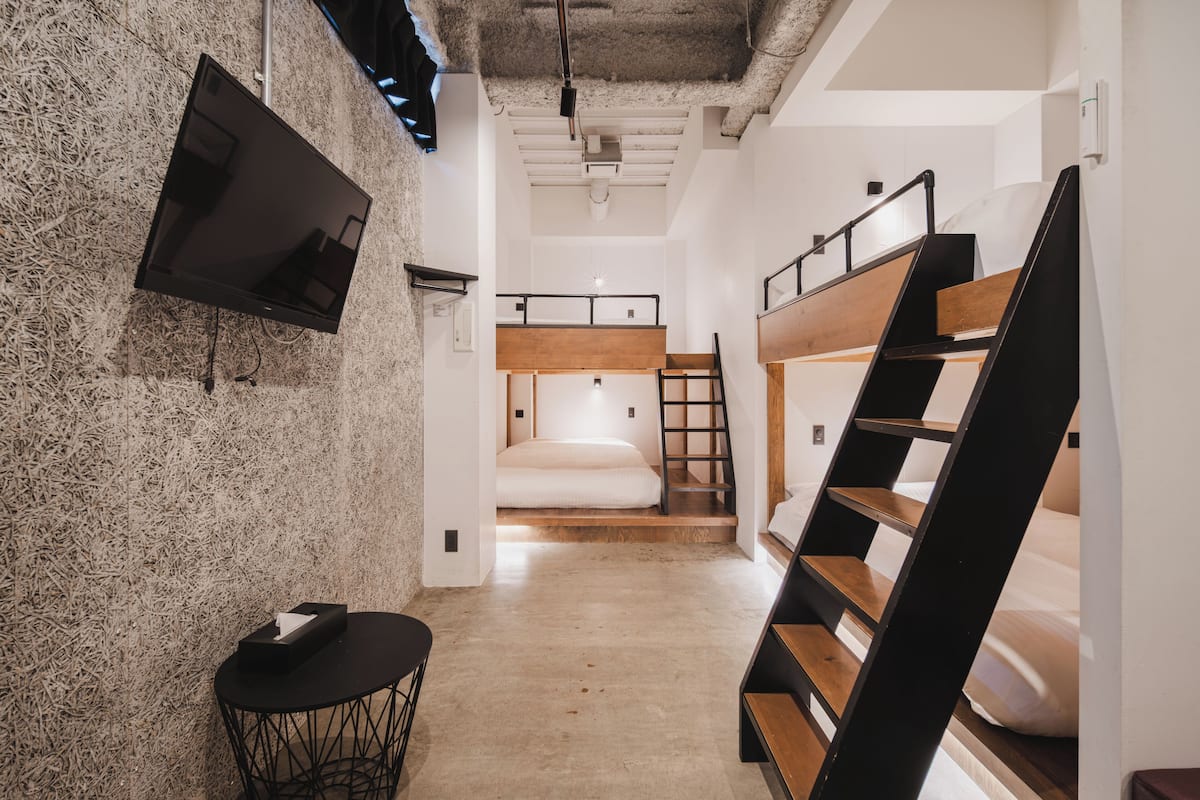 Un intérieur moderne avec des lits superposés, un téléviseur et une petite table.