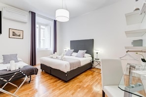 A modern hotel room with a large bed, a desk, a chair, and a hanging plant. - Residenza Le Gemelle di Roma (Rome)