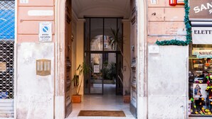 A hotel entrance with a glass door, potted plants, and a doormat. - Residenza Le Gemelle di Roma (Rome)