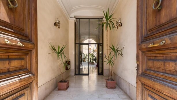 A corridor with wooden doors and potted plants. - Residenza Le Gemelle di Roma (Rome)