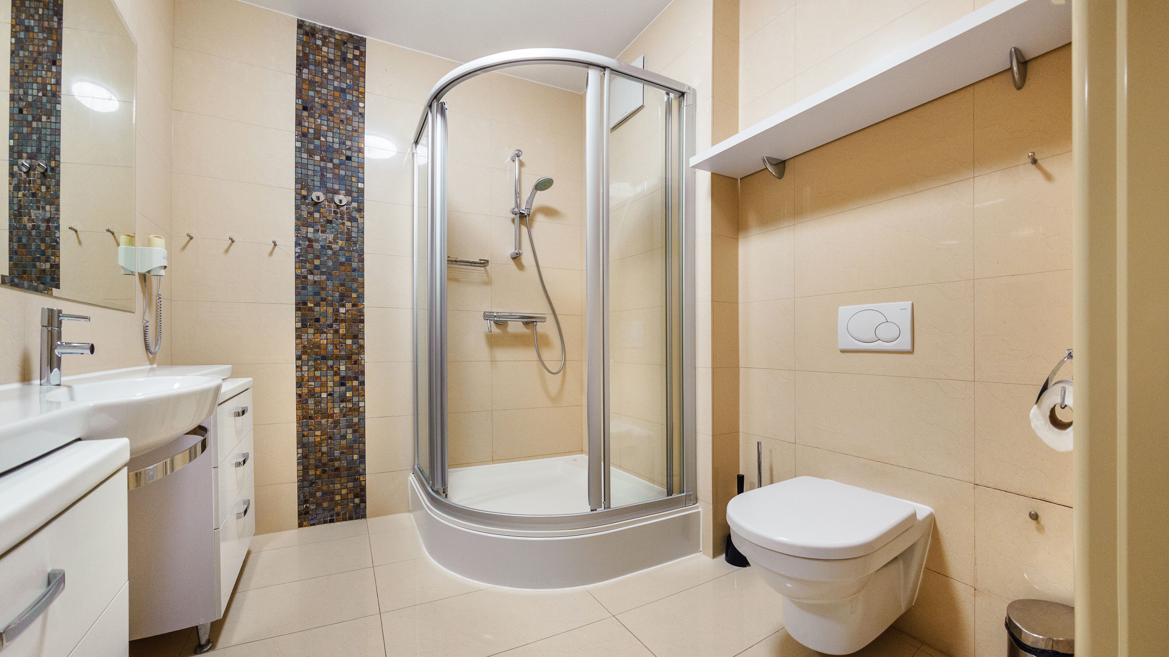 A modern bathroom with a glass shower enclosure, a white sink, and a toilet.