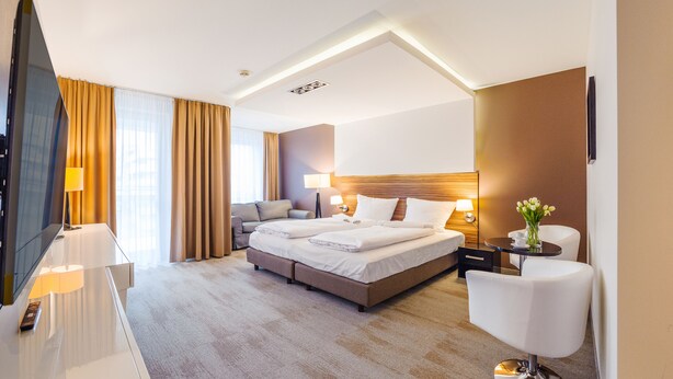 Une chambre d’hôtel moderne équipée d’un grand lit, d’un canapé, d’un bureau et d’une télévision.