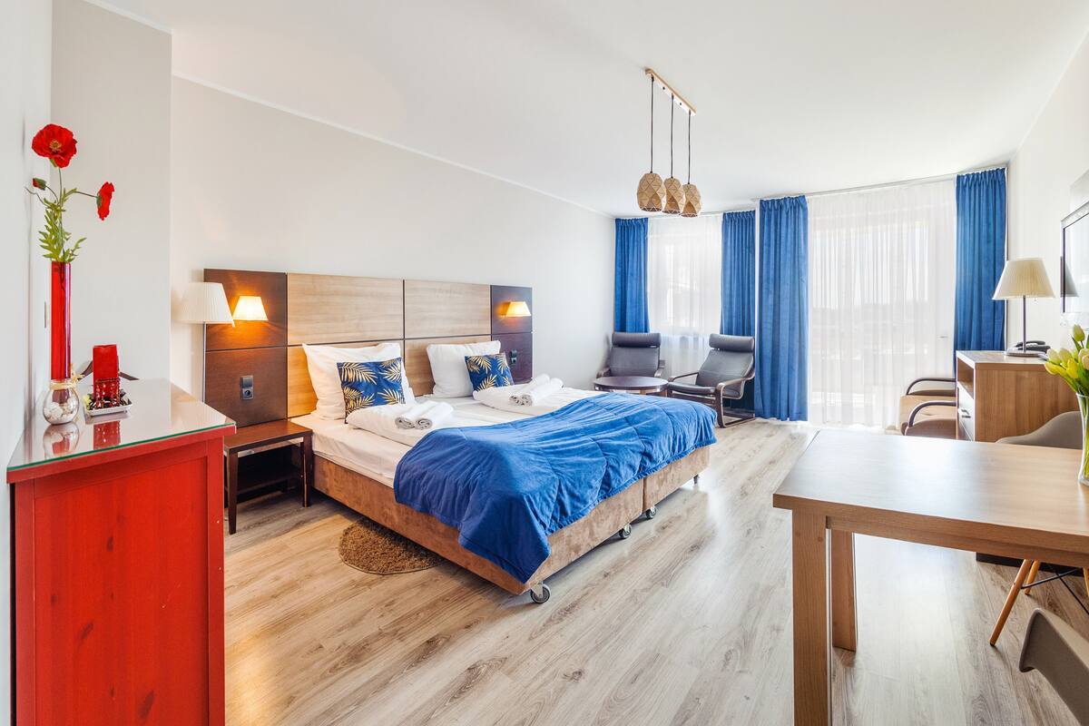 Una habitación de hotel moderna con cama, mesitas de noche, escritorio y una silla.