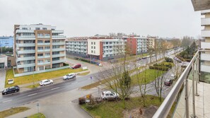 Ein modernes Mehrfamilienhaus mit mehreren Etagen, einem Parkplatz und einer Straße mit Autos.