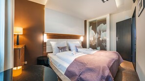 Ein modernes Hotelzimmer mit einem großen Bett, einem Nachttisch, einer Lampe und einem Kleiderschrank.