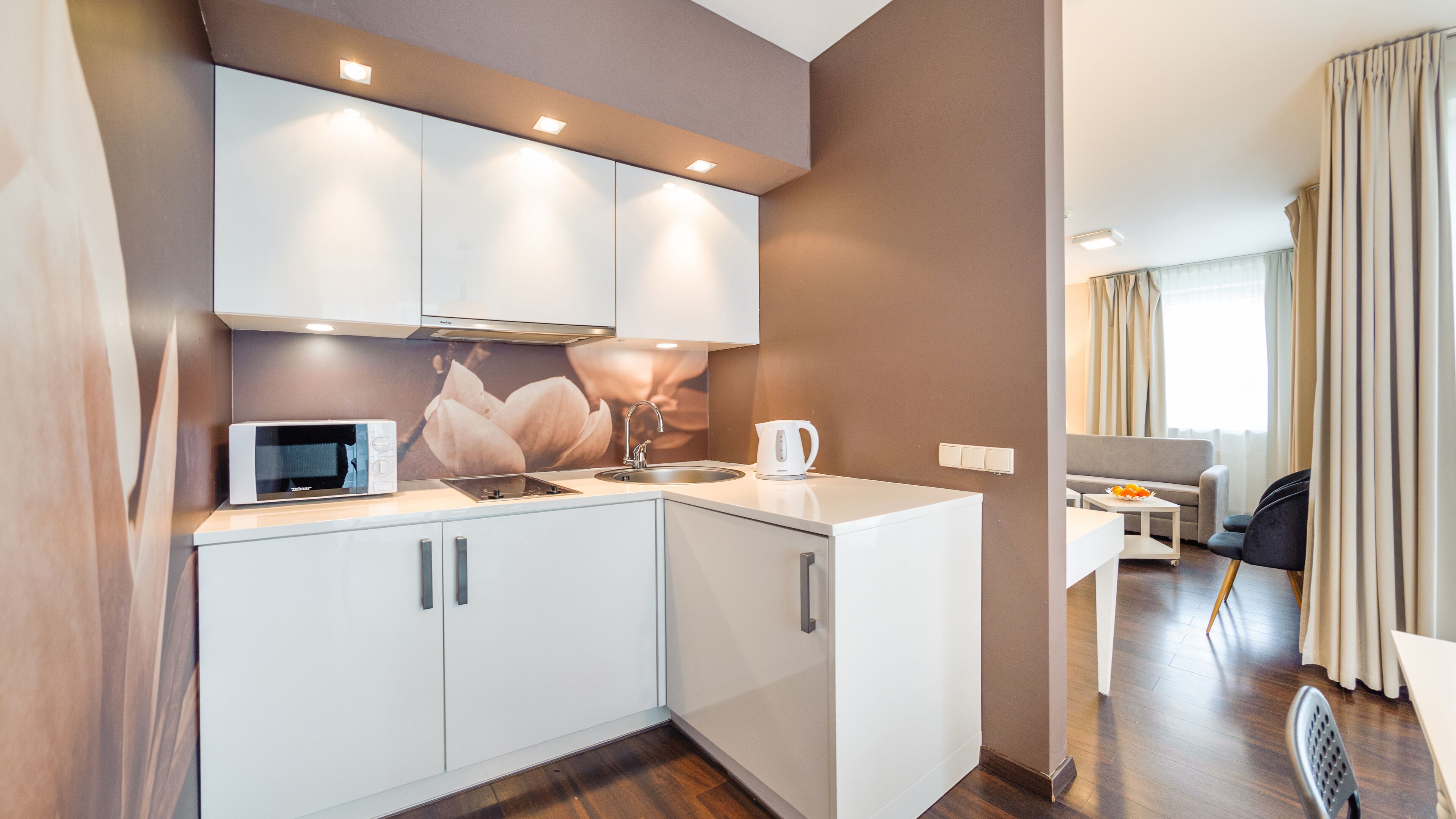 A compact hotel kitchen with a microwave, kettle, and sink.