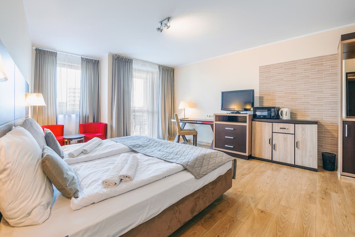 Una habitación de hotel moderna con cama, escritorio, televisor y kitchenette.