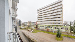 Ein mehrstöckiges Wohngebäude mit Balkonen, einem Parkplatz und einem kleinen Park mit Bäumen.