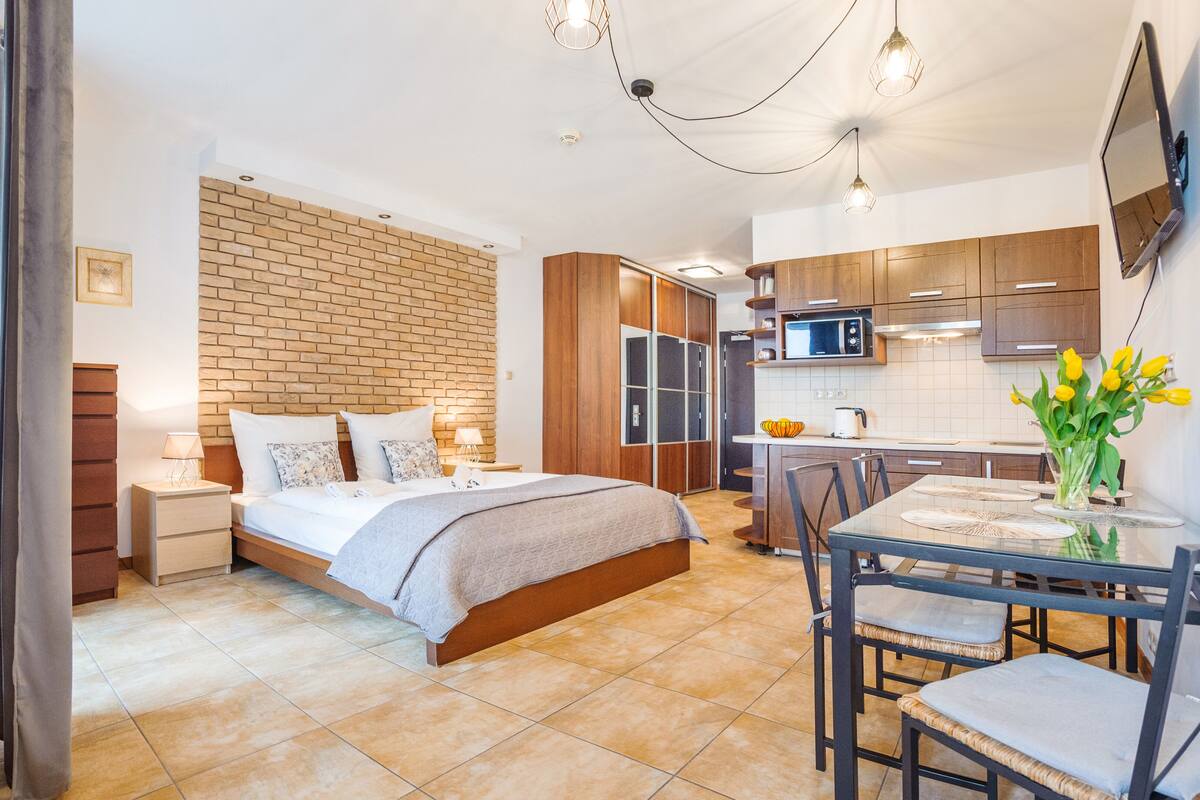 Un dormitorio moderno con una cama grande, baño privado, kitchenette y comedor.