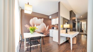 Une chambre d’hôtel moderne dotée d’un coin repas, d’une grande fresque florale, d’un téléviseur à écran plat et d’un minibar.