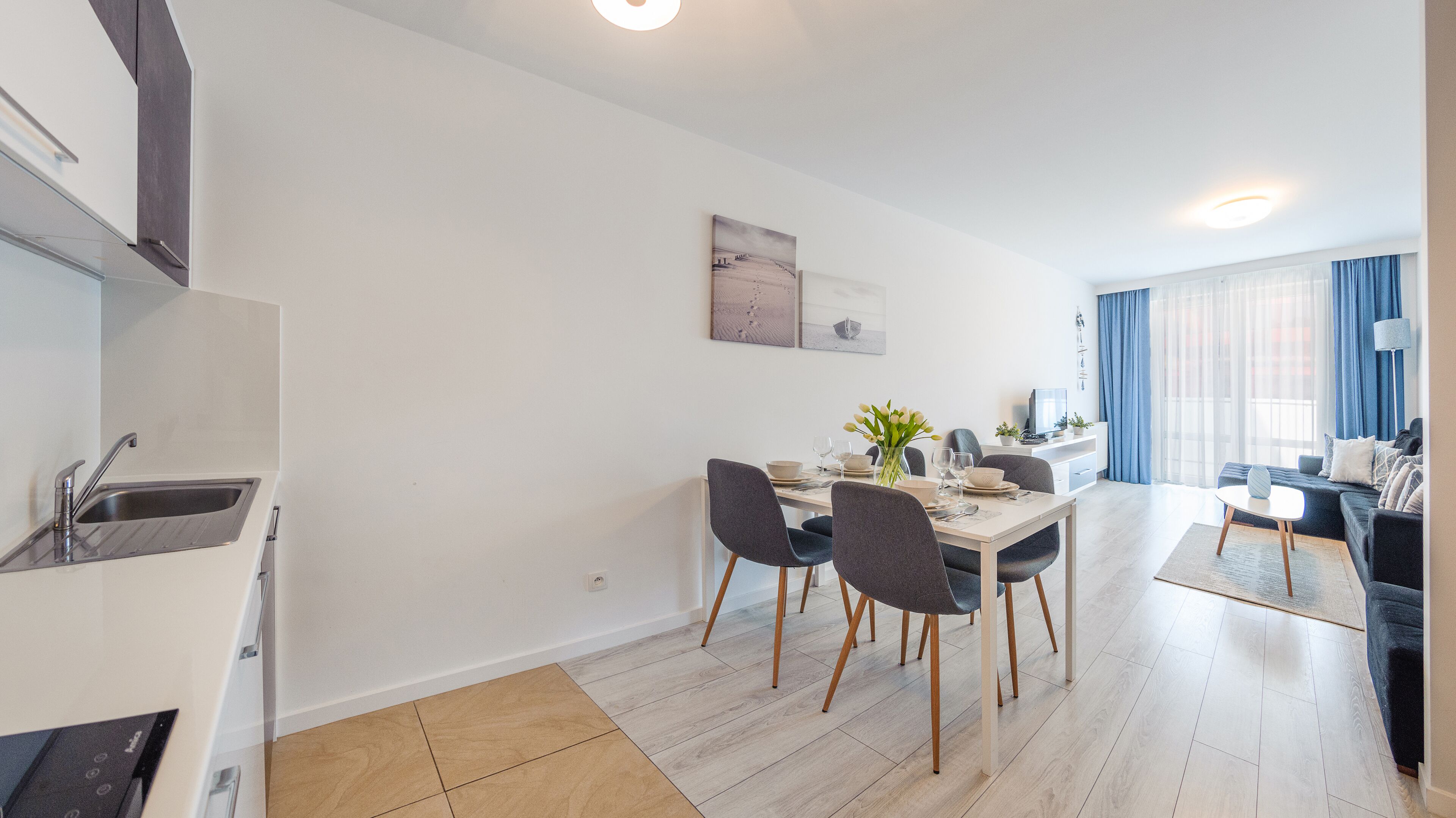 Een moderne keuken met een inbouwspoelbak en een eethoek met een tafel en stoelen.
