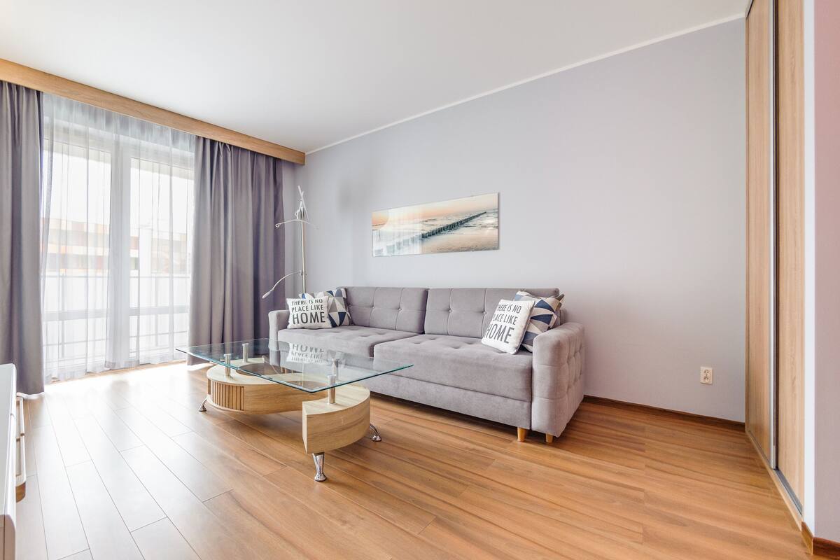 Un salon moderne avec un canapé, une table basse en verre et un téléviseur.