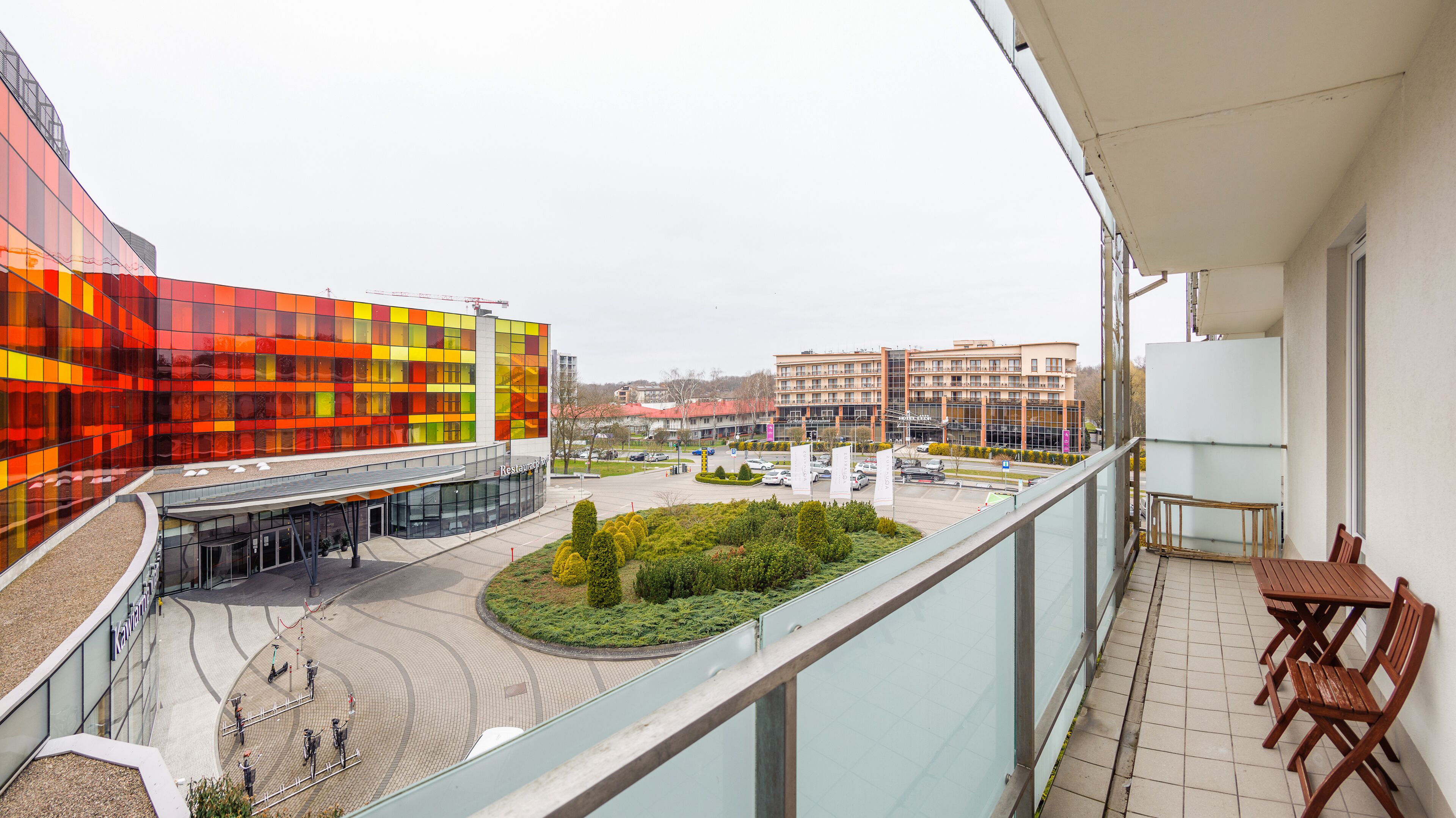 A modern building with a colorful facade, a central courtyard with greenery, and a view of surrounding buildings.