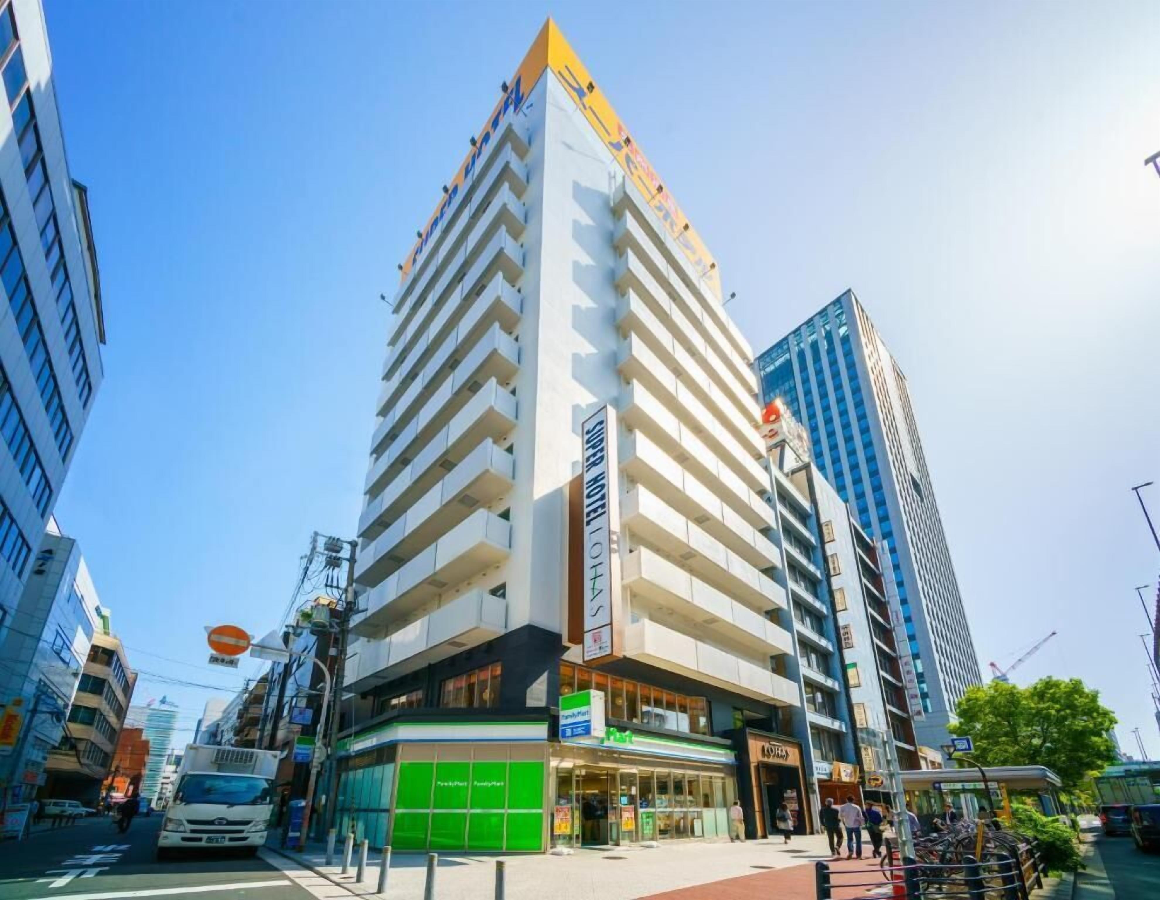 A modern hotel with multiple floors, a prominent entrance, and a green storefront at the ground level.