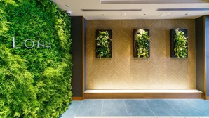 A modern hotel lobby with a green wall, three vertical planters, and a herringbone-patterned floor. - Super Hotel Premier Osaka Honmachi (Osaka)