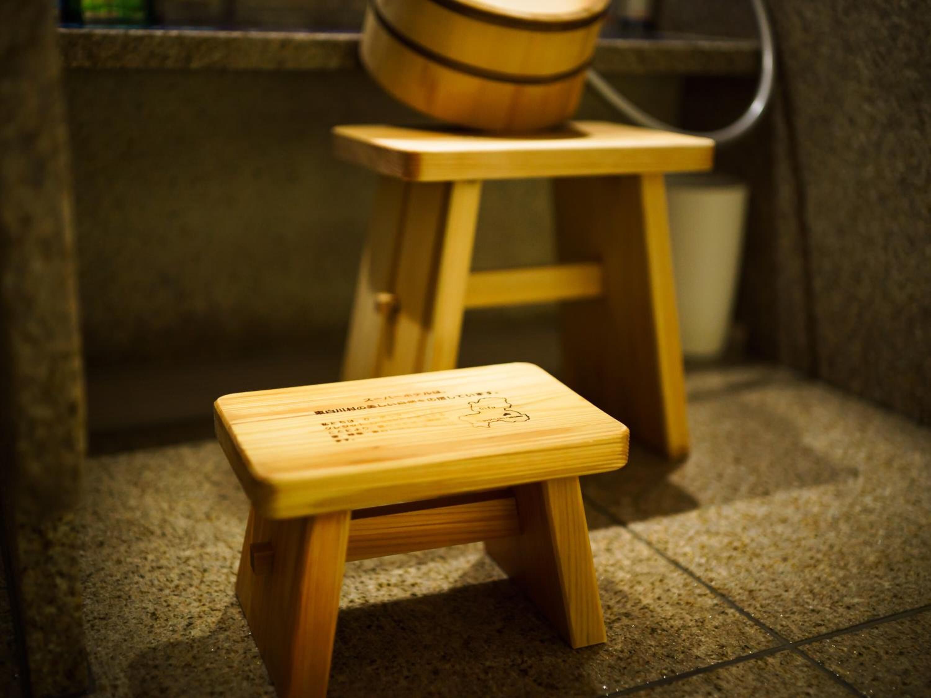 Un taburete de madera con una pequeña mesa en la parte superior, sobre un piso de baldosas.