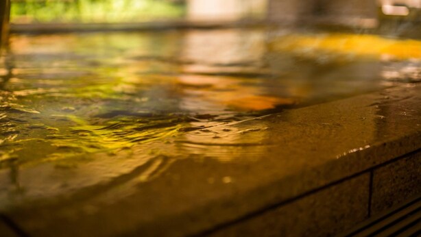A close-up of a wet, reflective surface, likely a pool or hot tub, with a blurred background suggesting an outdoor setting. - Super Hotel Premier Osaka Honmachi (Osaka)