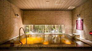A hot spring bath with a view of bamboo and rocks, a wooden ceiling, and a sign with Japanese text. - Super Hotel Premier Osaka Honmachi (Osaka)