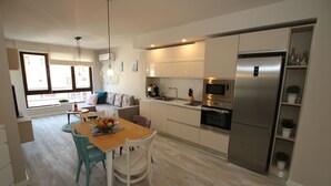 A modern kitchen with a dining area, built-in appliances, and a view through the window. - Apartments Angelov (Varna)