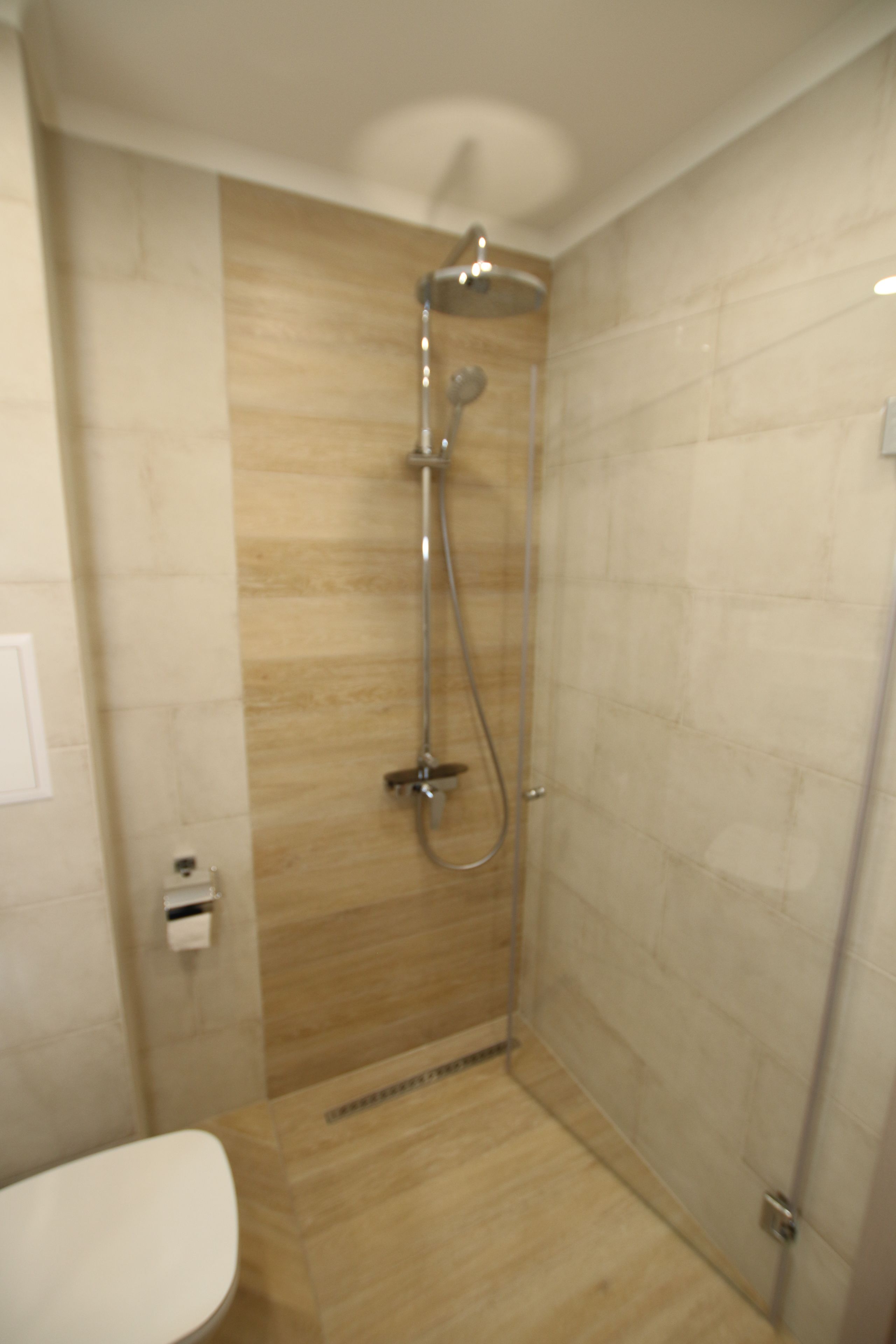 Un baño con ducha, inodoro y dispensador de toallas.