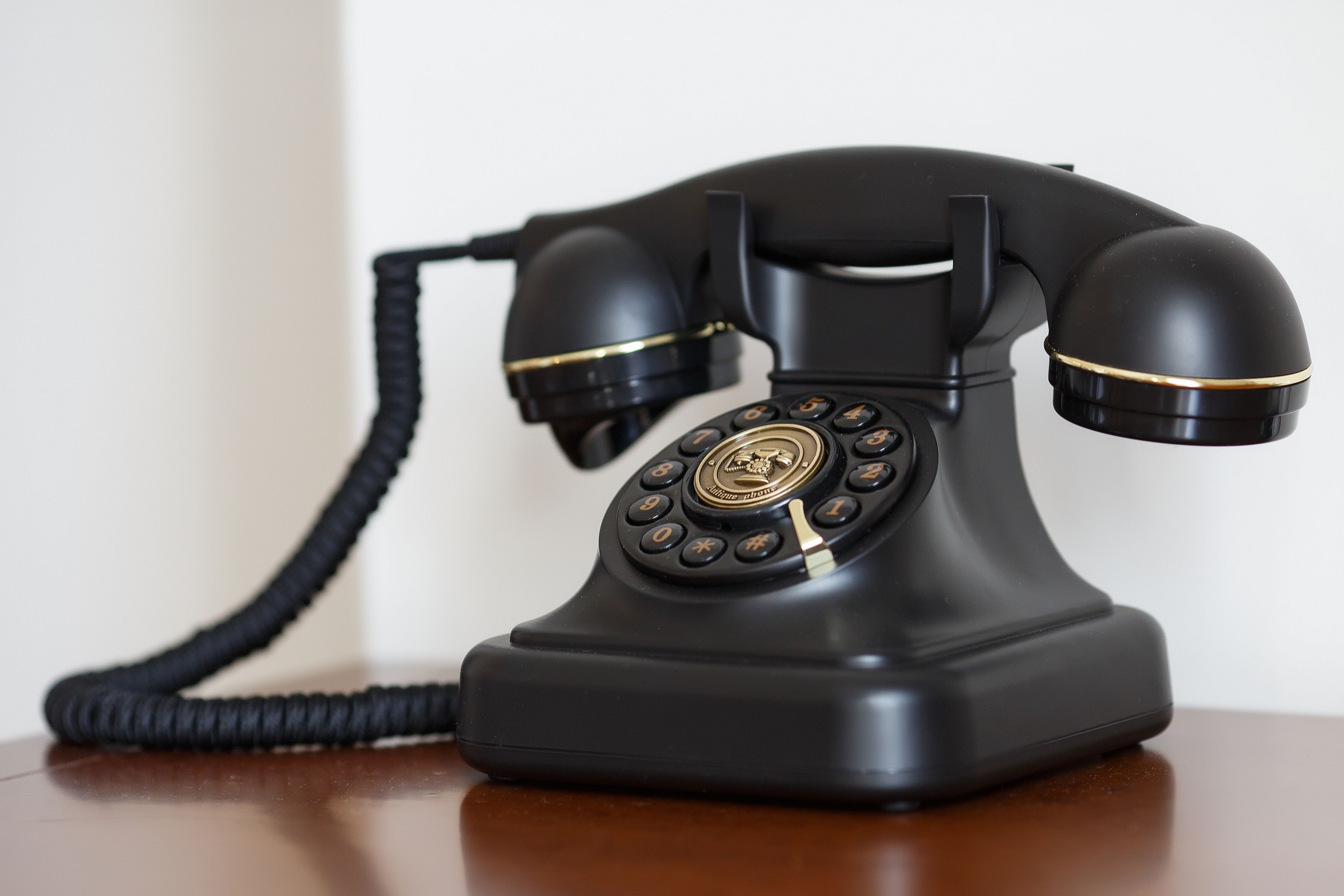 Een zwarte draaischijf telefoon op een houten oppervlak.