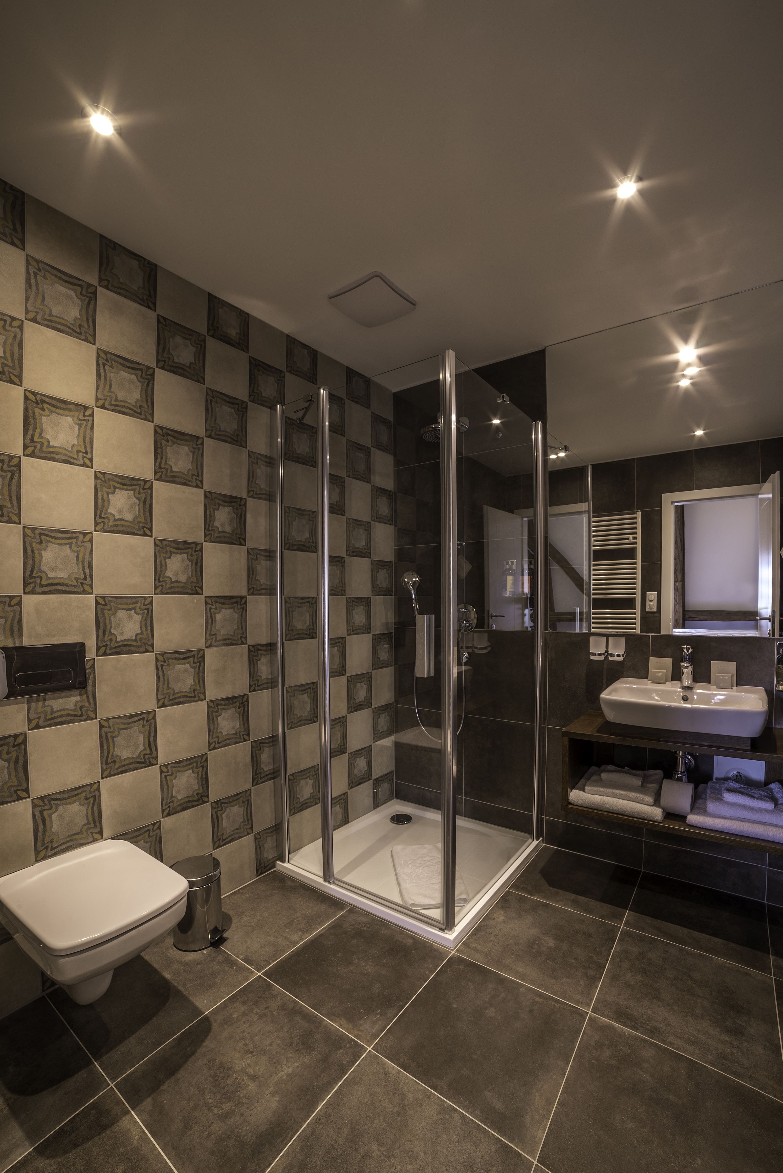 A modern bathroom with a glass-enclosed shower, a white toilet, and a sink with a mirror above it.