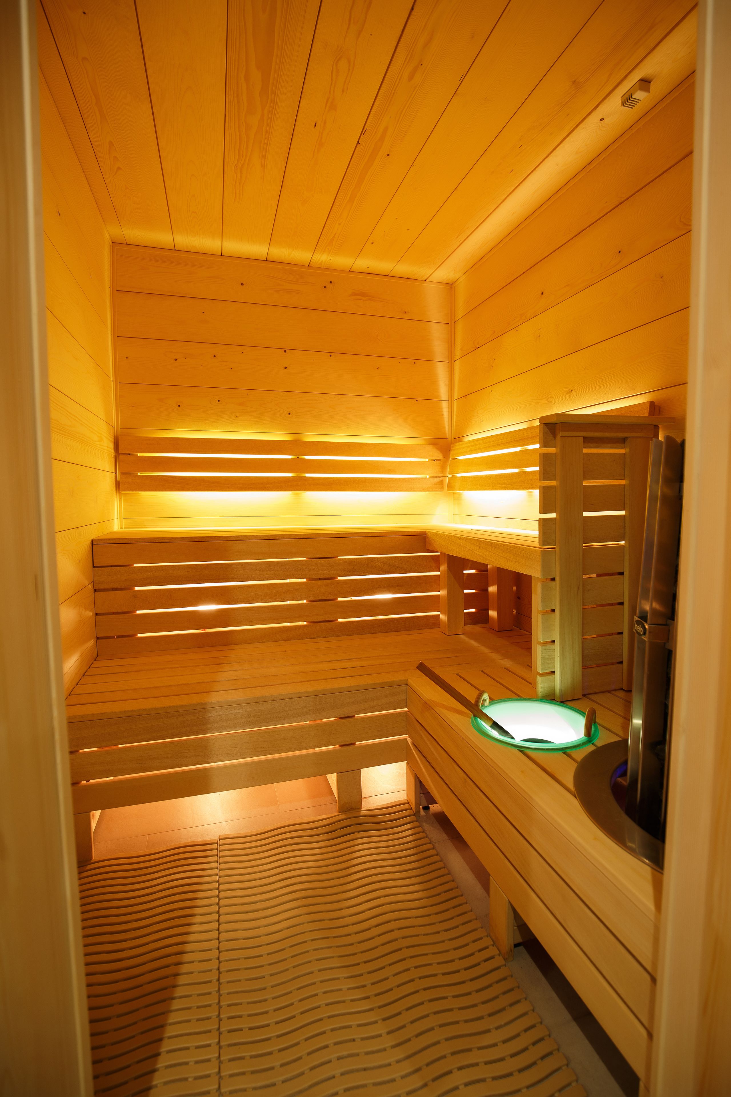 Una sauna con bancos de madera y un banco con calefactor integrado.