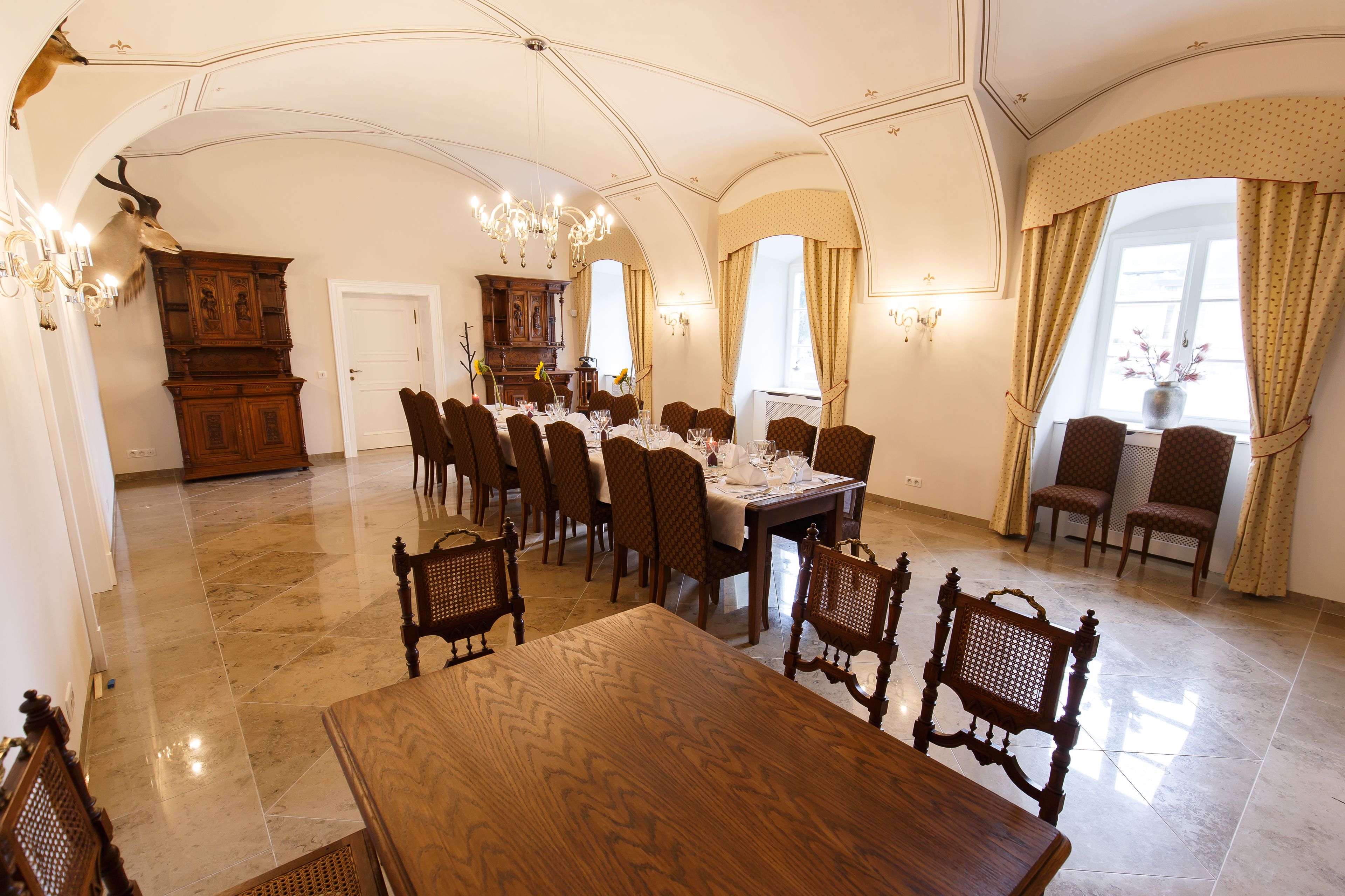 Comedor con una gran mesa de madera, varias sillas y una lámpara de araña.