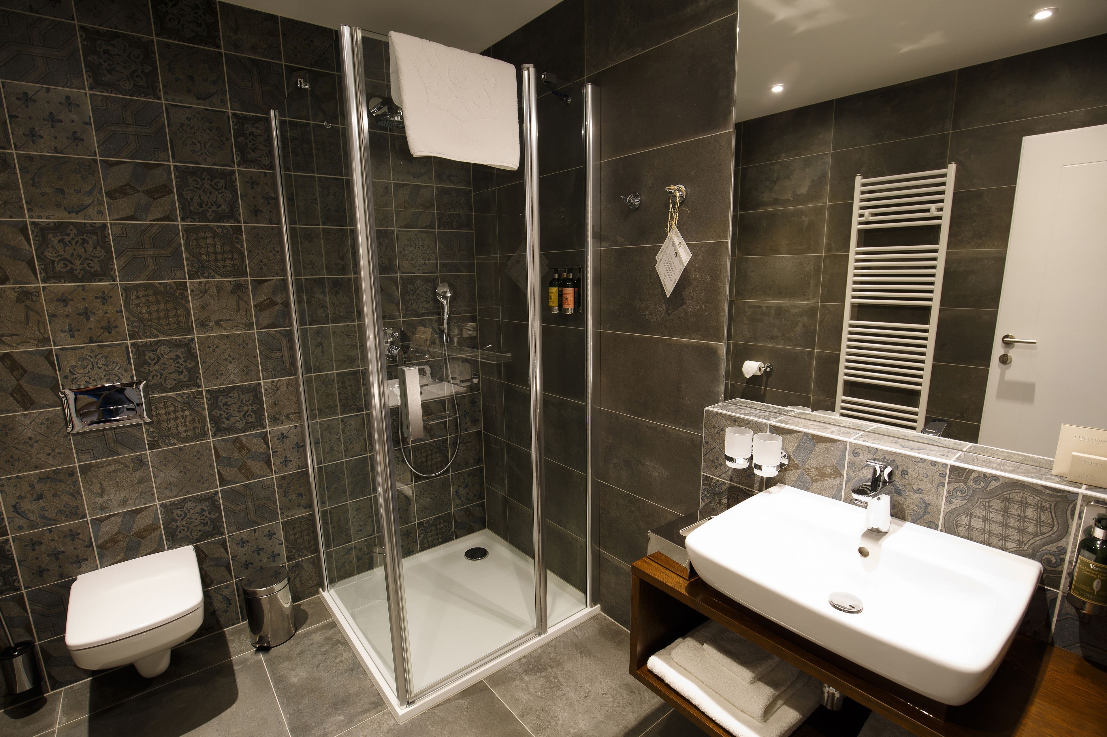 Een moderne badkamer met een douchecabine van glas, een witte wastafel en een grote spiegel.