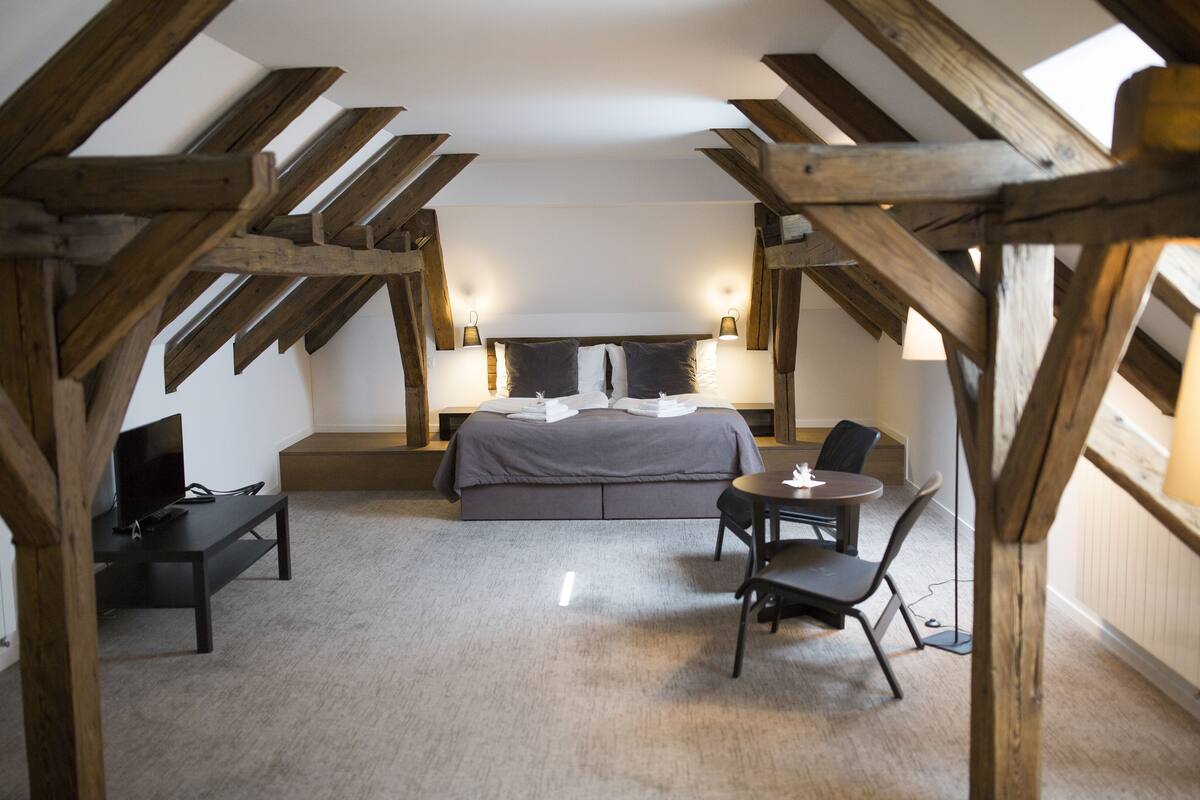 A bedroom with a bed, bedside tables, a desk, and a chair.