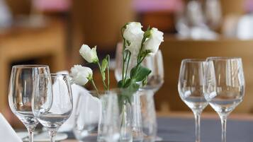 Una mesa de comedor dispuesta con copas de vino y un florero con flores blancas.