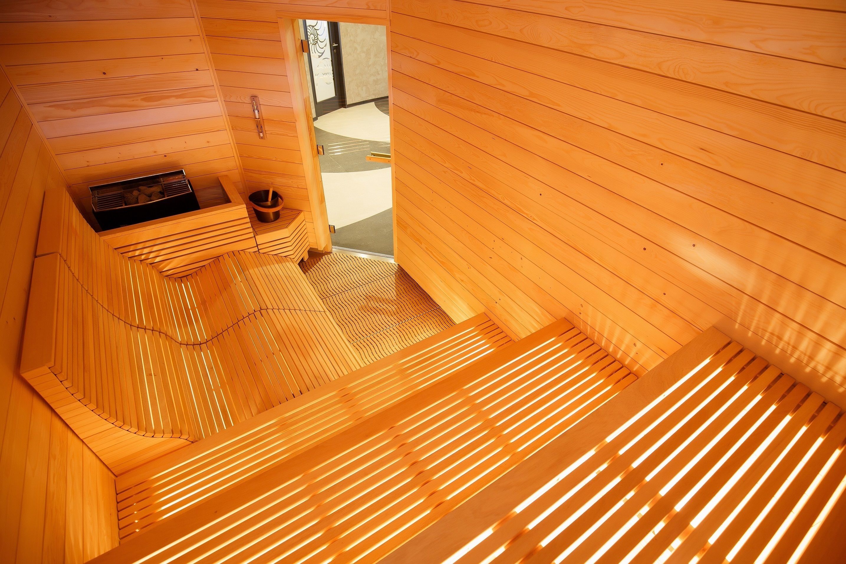 A sauna room with wooden slats and a bench.