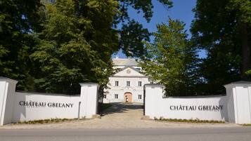 Ein imposanter Eingangsbereich mit einer weißen Mauer und einem Tor, auf dem "CHÂTEAU GBEANY" steht.