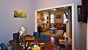 A dining area with a wooden table set for a meal, a sofa, and a coffee table. - Downtown Savannah Oasis 4 BR 3 BA (Savannah)