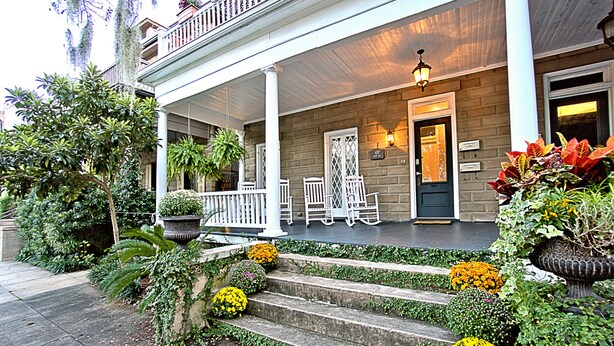 A two-story building with a covered porch, steps leading to the entrance, and potted plants. - Downtown Savannah Oasis 4 BR 3 BA (Savannah)